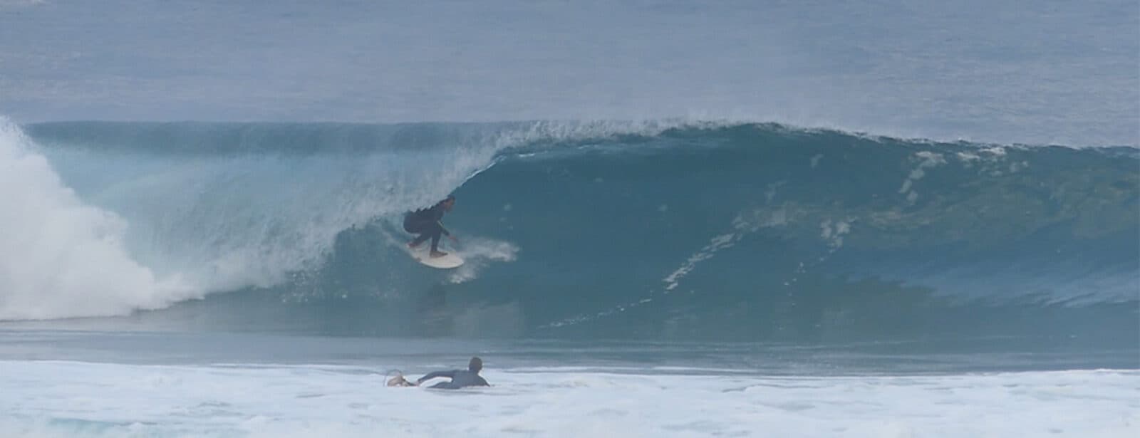 Surfista dentro de um tubo numa onda grande